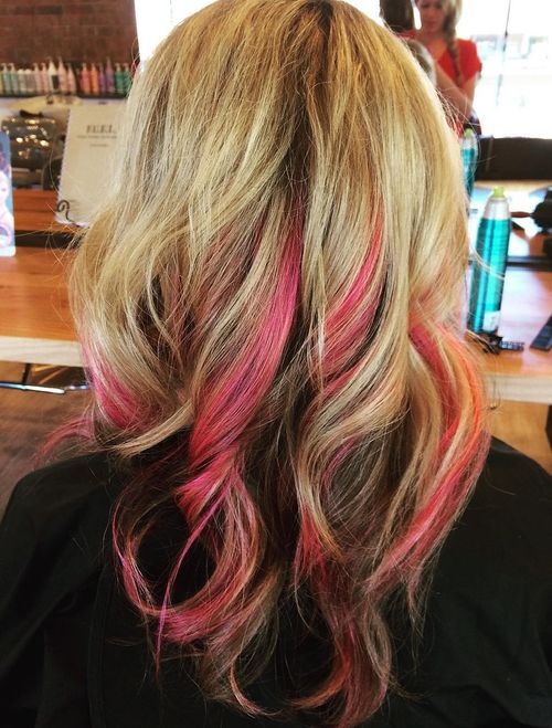 Blonde hair with pink peekaboo highlights, wavy texture, medium length, hidden color beneath blonde base