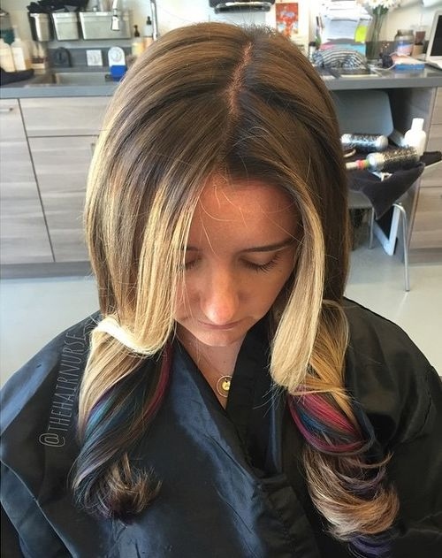 Brown base with blonde peekaboo highlights and hidden red blue tones in wavy medium length hair