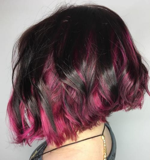 Dark base with vibrant pink peekaboo highlights, wavy bob, textured layers, hidden color beneath outer strands