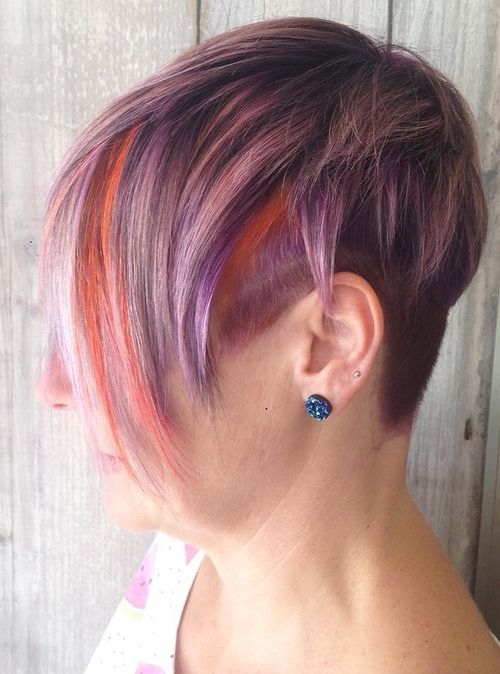 Short purple hair with vibrant orange peekaboo highlights under layers, textured and styled with a shaved side