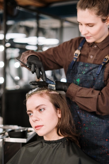 Hairdresser applying hair dye to client hair using a brush for peekaboo coloring technique