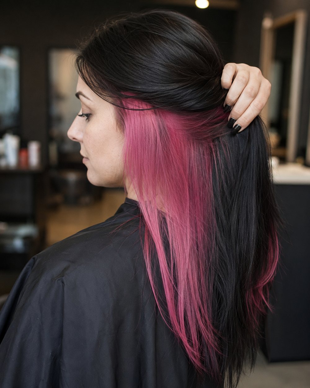 Black hair lifted to reveal a vivid pink peekaboo underlayer
