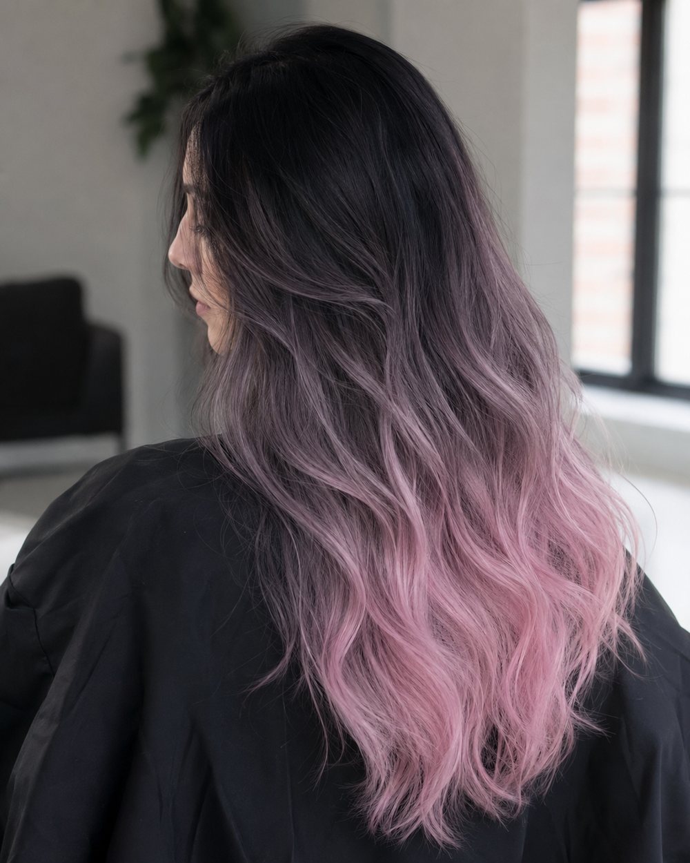 Long wavy hair blending from black through smoky mauve to pastel-pink ends