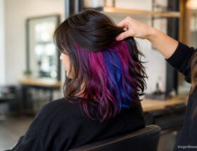 Salon reveal of blue and magenta peekaboo color beneath dark brunette hair.