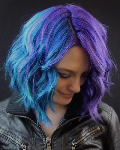 Half blue and half purple split dye hair styled in shoulder length waves